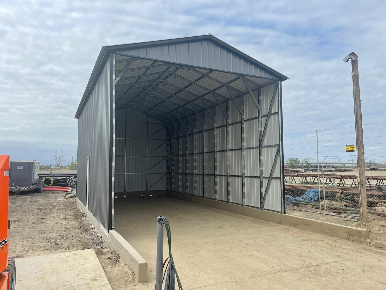 A partially enclosed steel building with one end closed in, the shell a cabin build-out starts from