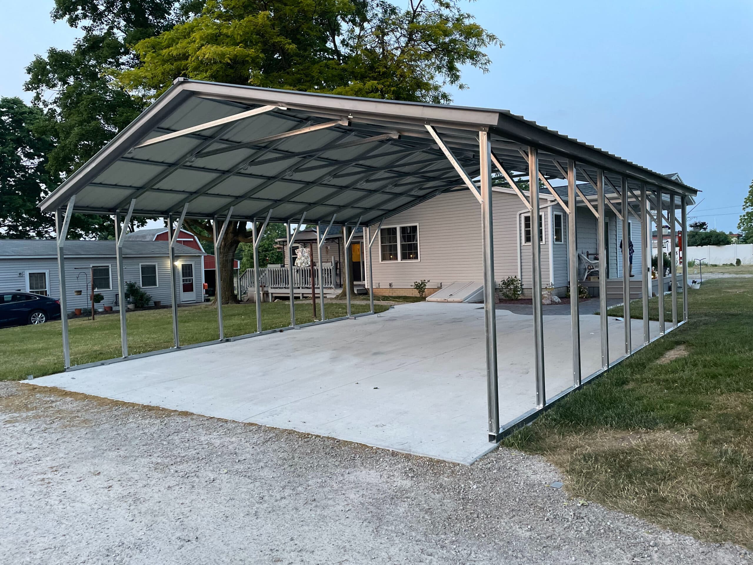 Vertical-roof metal carport sheltering a pickup truck